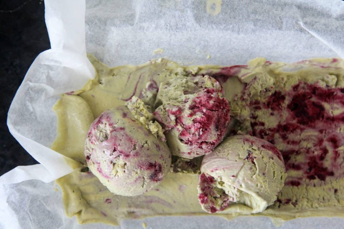 Scoops of matcha blackberry no churn semifreddo iced dessert sits in a lined loaf tin.