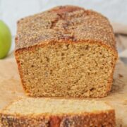 The light crumb of a Apple butter Cake is visible while sitting on parchment paper with a brown cloth behind.