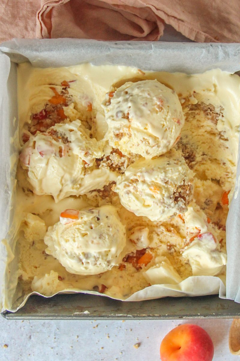 Apricot Crumble Semifreddo sits in a square metal tin on a light grey background.