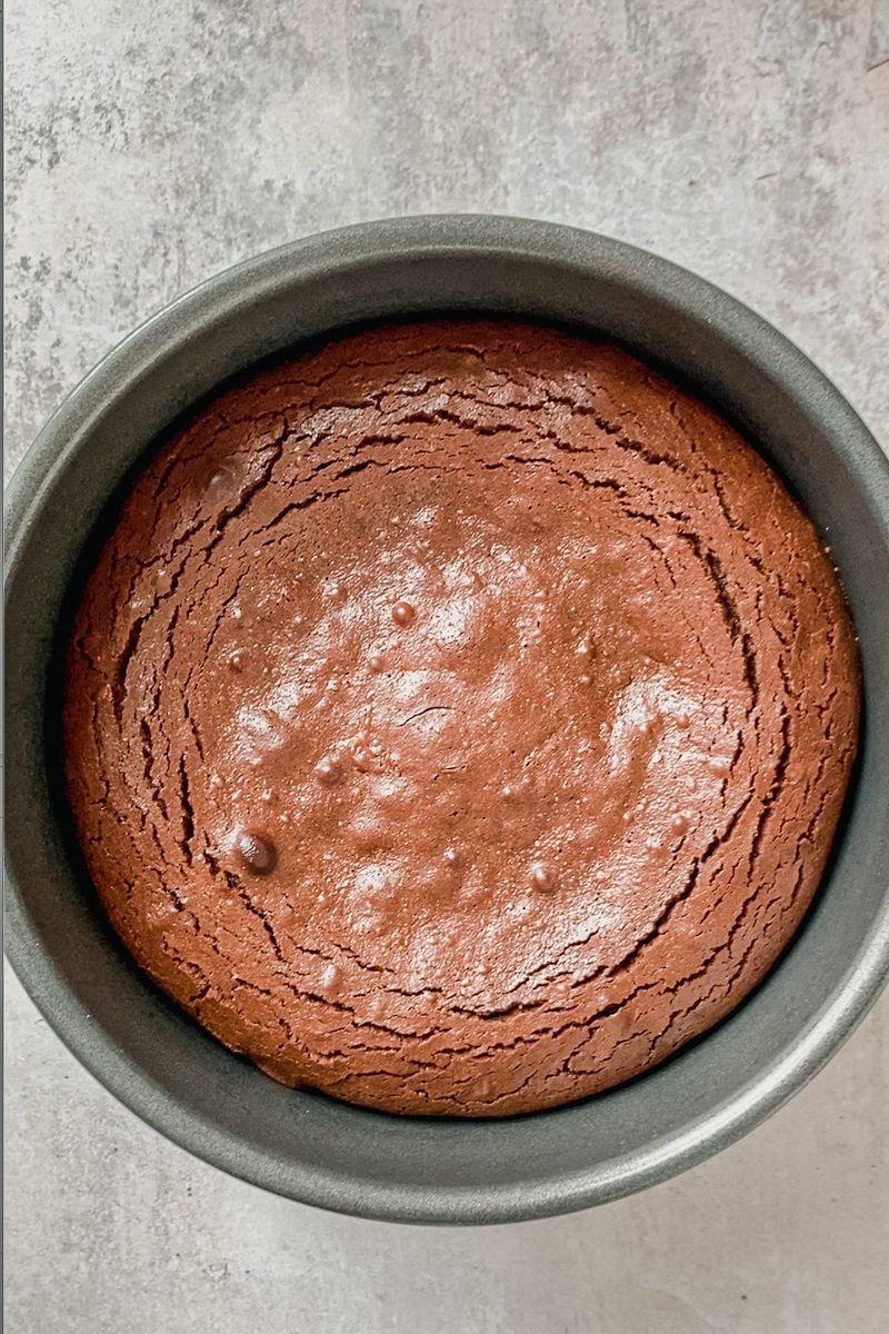 Baked smore pie chocolate filling sits in a round metal cake tin on a gray surface.