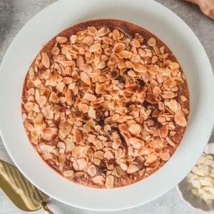 Portuguese Almond Cake sits on a ceramic plate on a light gray surface.