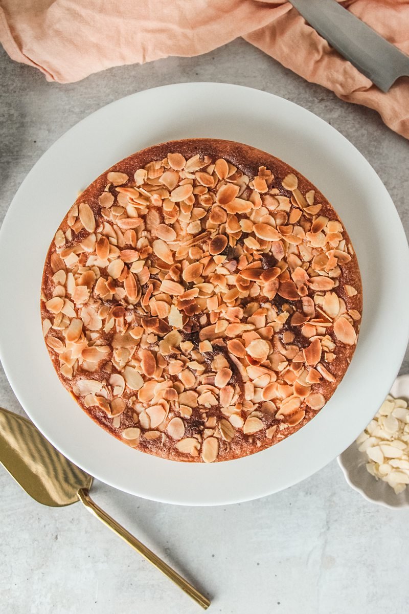 Portuguese Almond Cake sits on a ceramic plate on a light gray surface.