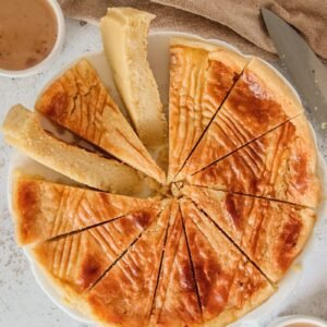 Boterkoek or Dutch Butter Cake cake sits sliced up on a white plate above a gray surface.