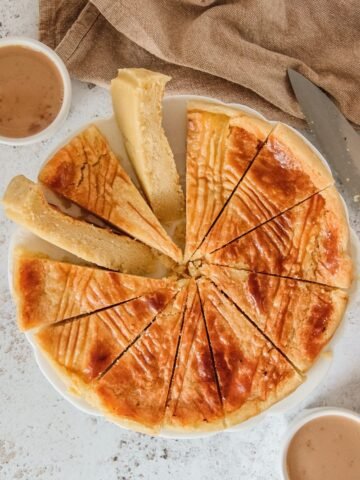 Boterkoek or Dutch Butter Cake cake sits sliced up on a white plate above a gray surface.