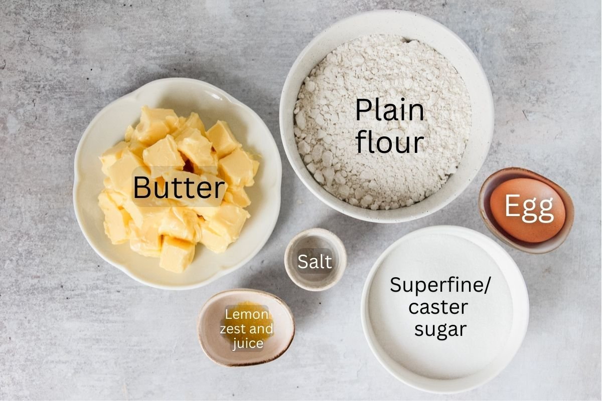 Ingredients for Dutch Butter Cake sit in a variety of bowls and plates on a gray surface.