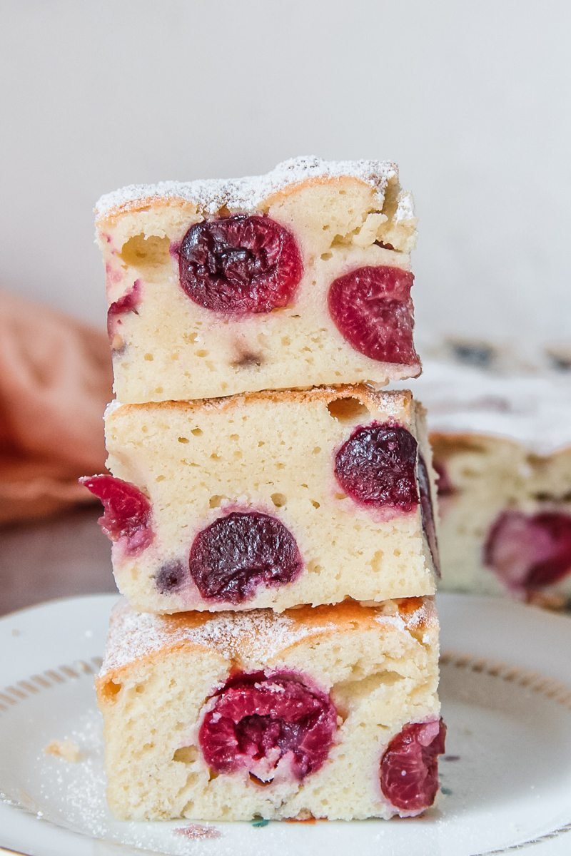 Slices of Bublanina cake are stacked on top of each other on a plate.