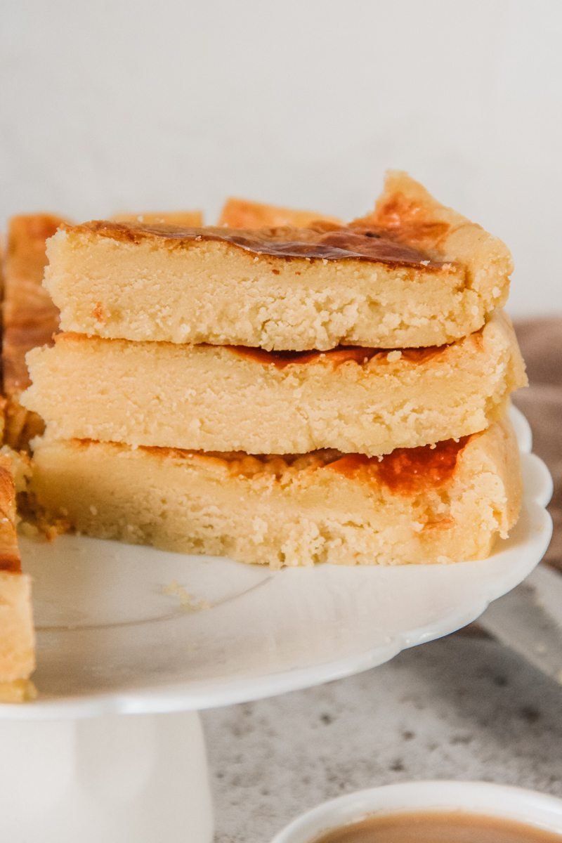 Slices of Butter Cake sit on top of each other on a cake stand above a gray surface.