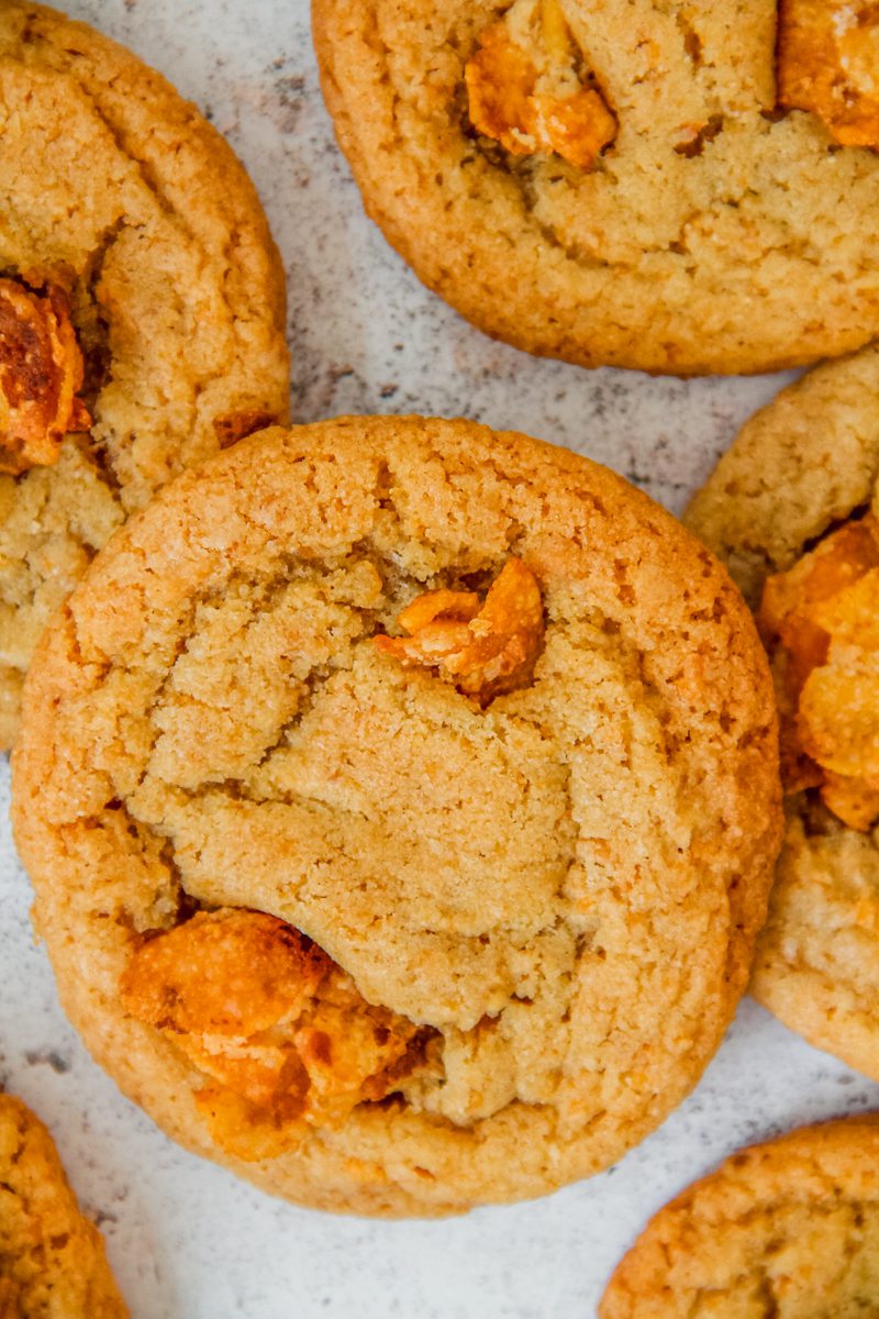 Cornflake cookies topped with a cornflake crunch sit on a light gray surface.