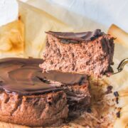 A slice of Chocolate cheesecake sits on a cake server above the remaining cheesecake.