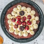 A no bake chocolate pudding cherry pie sits in a black metal pie dish on a light gray surface.