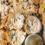Coffee chocolate chip frozen custard sits with three scoops resting on top of the ice cream and an ice cream resting beside in the tin.