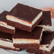Czech chocolate cheesecake pieces are stacked on top of each other on a white scalloped plate.