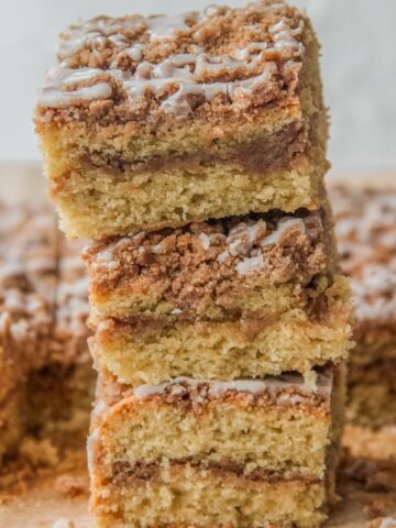 Slices of Dairy Free Coffee Cake sit stacked on top of each other with the cinnamon streusel center and strewn glaze visible.