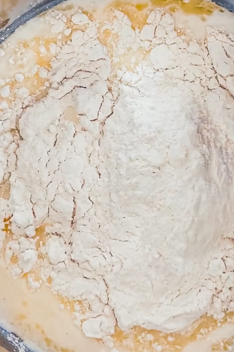 Flour sits on top of a melted butter and milk mixture in a saucepan.