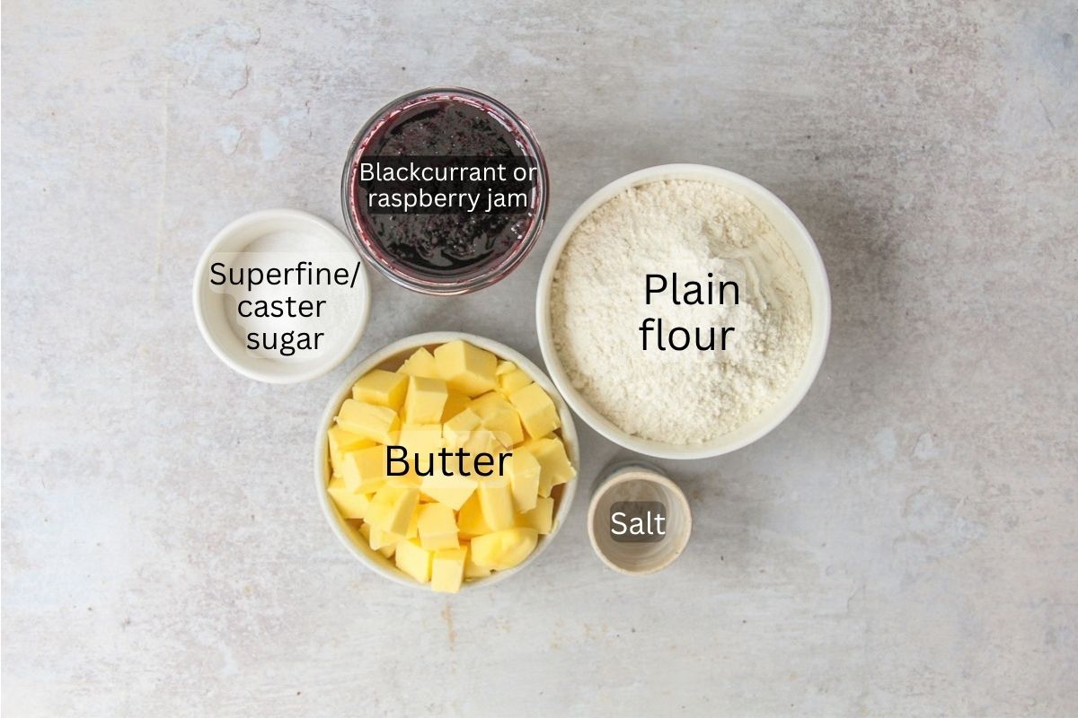 Ingredients for Estonian Jam Bars (Klassikaline Purukook) sit in a series of bowls on a gray surface.