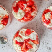 Eton Mess is served up in individual glasses on a light gray surface.