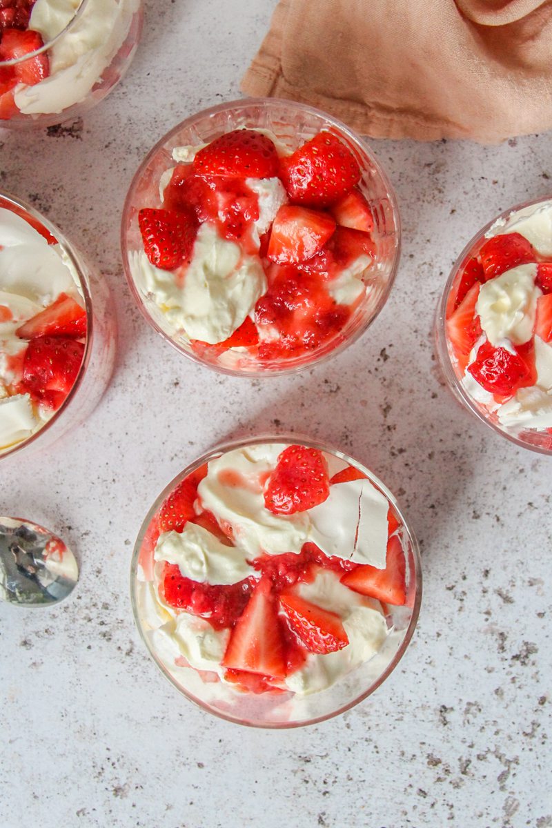 Eton Mess is served up in individual glasses on a light gray surface.