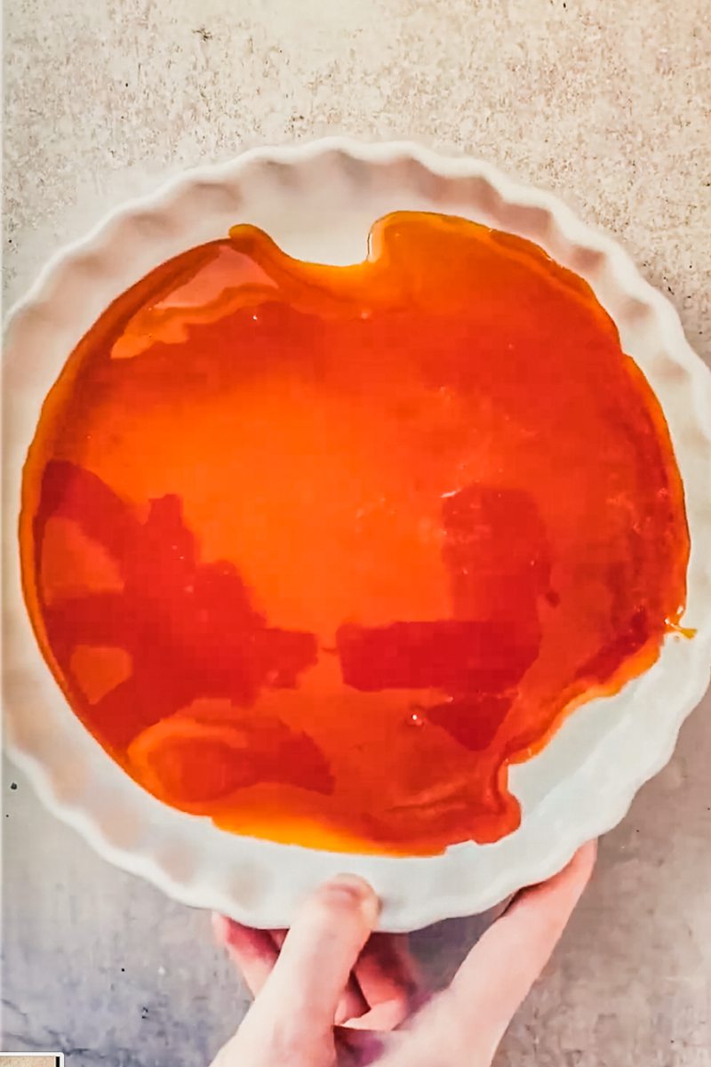 Caramel sits in a white ceramic baking dish on a gray surface.