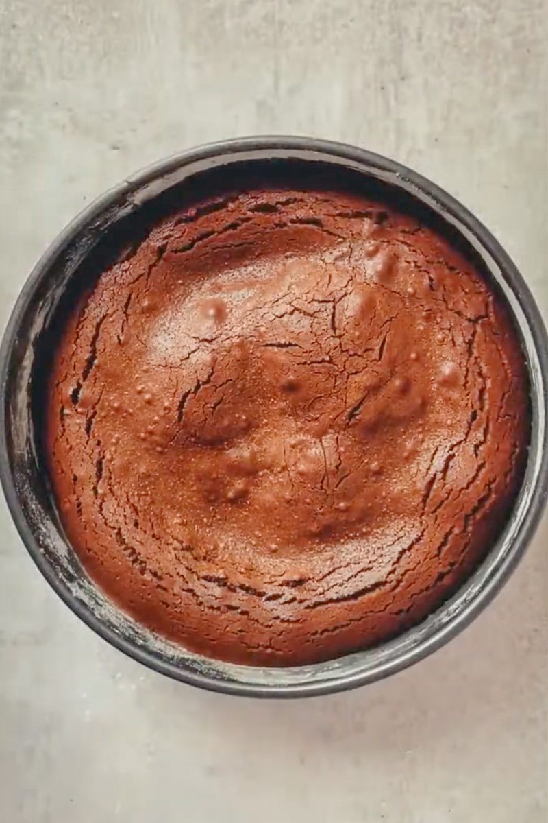 A baked French chocolate cake sits in a cake tin on a gray surface.