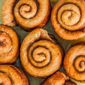 Gemberbolus or Dutch Ginger Rolls sit on a ceramic plate covered in syrup.