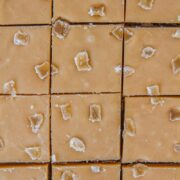 A close up of lines cut into Ginger Crunch Slice topped with pieces of crystallized ginger.