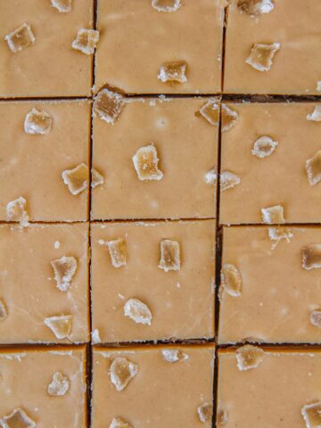A close up of lines cut into Ginger Crunch Slice topped with pieces of crystallized ginger.