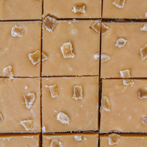 A close up of lines cut into Ginger Crunch Slice topped with pieces of crystallized ginger.