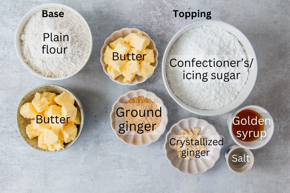 Ingredients for Ginger Crunch Slice sit in a series of bowls and plates on a gray surface.