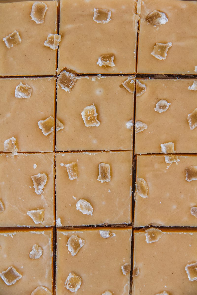 A close up of lines cut into Ginger Crunch Slice topped with pieces of crystallized ginger.