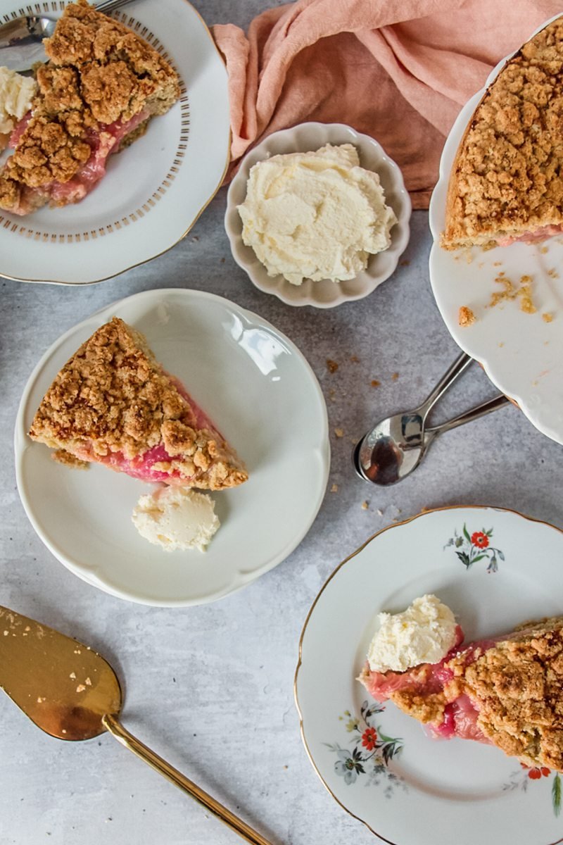 Slices of Icelandic Rhubarb Happy Marriage Cake sit on individual serving plates on a gray surface.