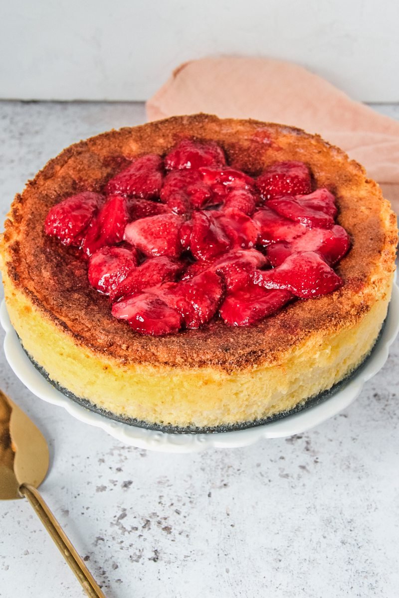 Hungarian Rice Pudding Cake is served up with homemade chunky strawberry jam on a light gray surface.