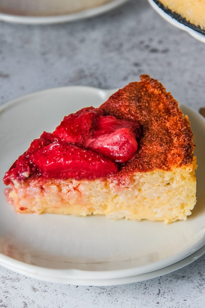 A slice of Hungarian rice pudding cake is served up on a white plate on a light gray surface.