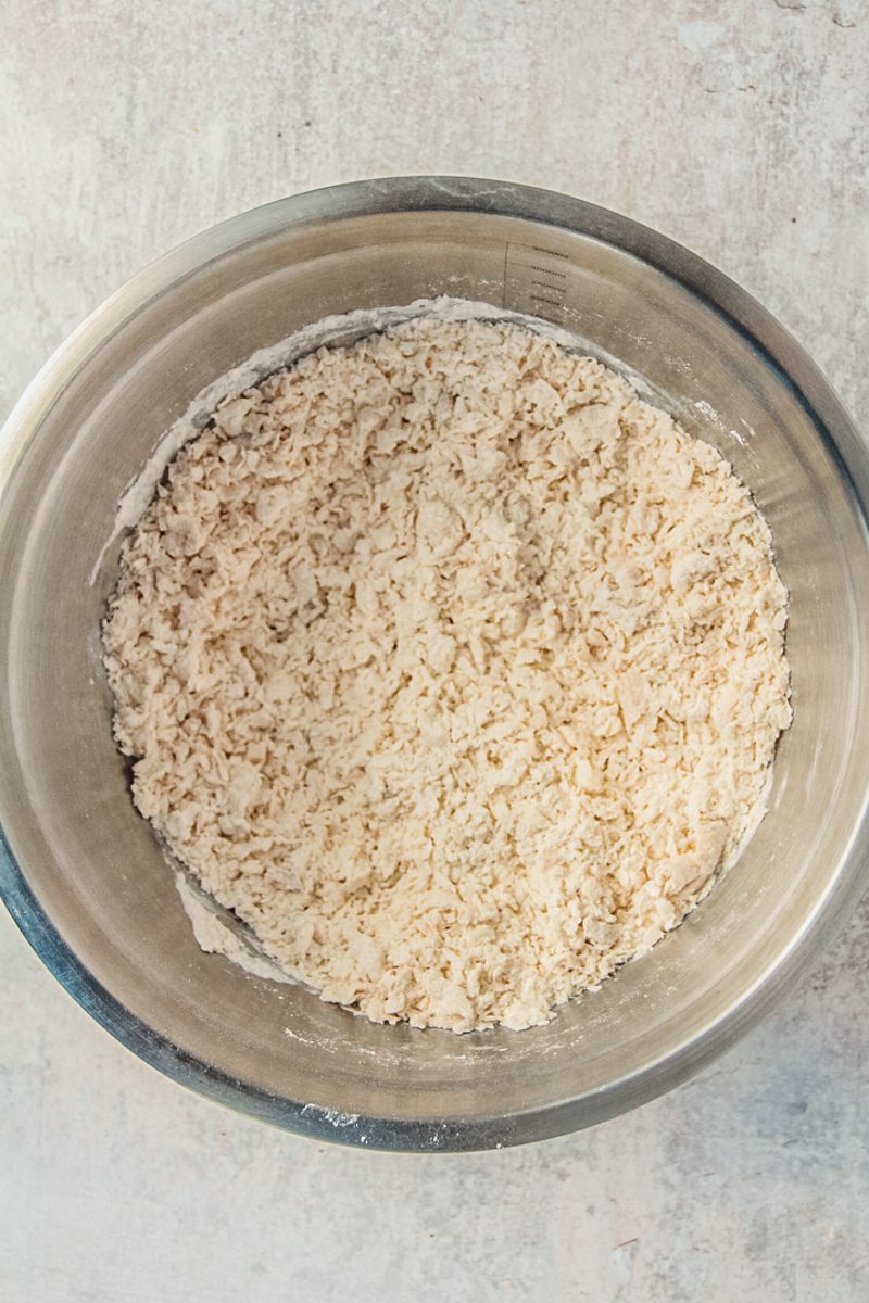 A shaggy dough sits in a stainless steel bowl on a gray surface.