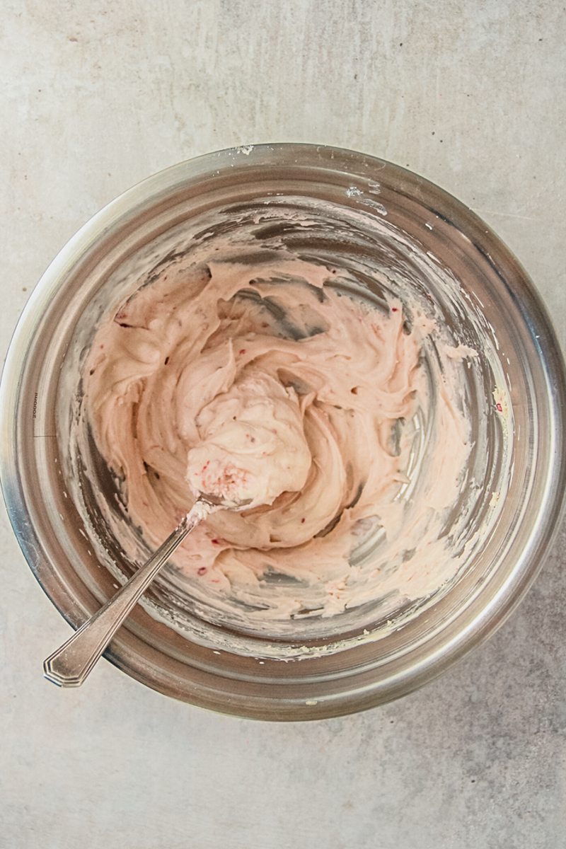 A jam cream mixture sits in a stainless steel bowl on a gray surface.