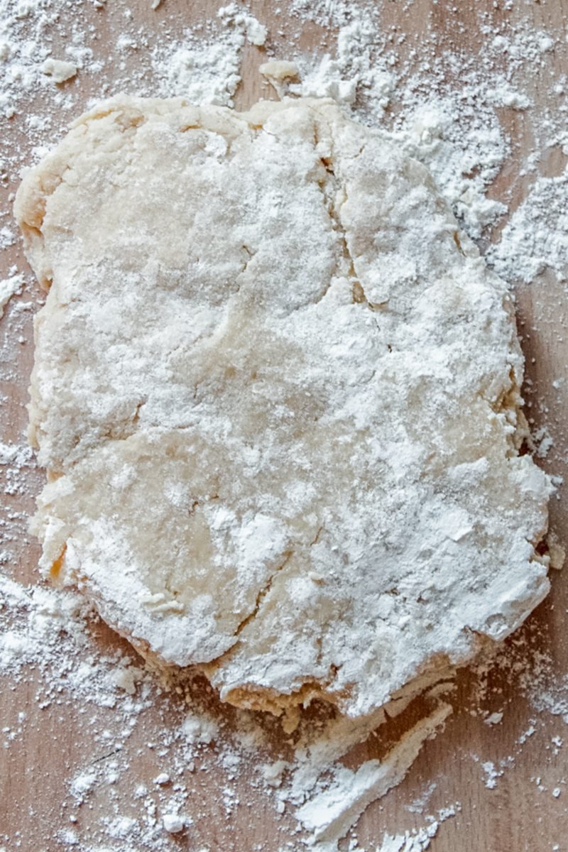 Pie pastry sits on a floured benchtop.