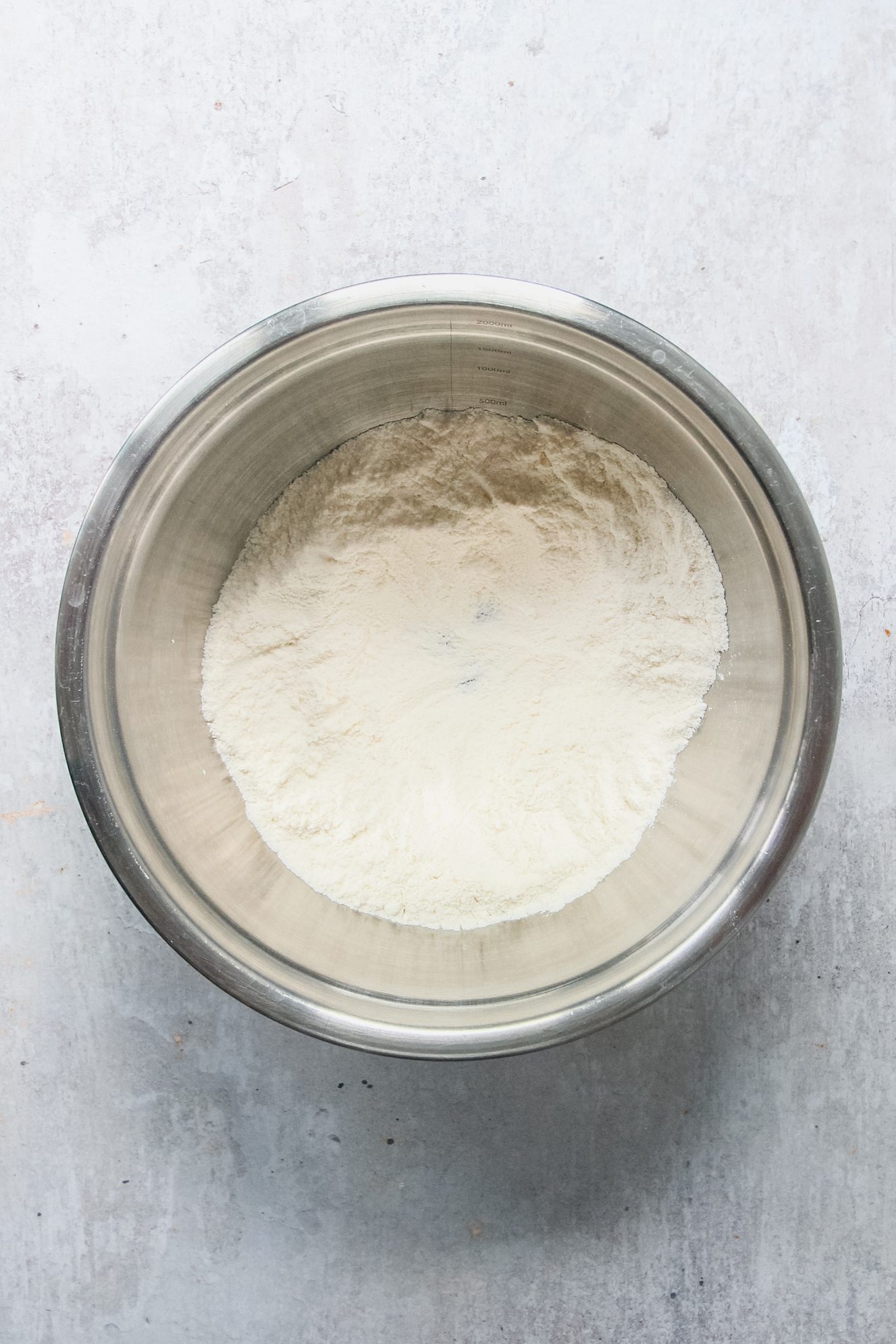 Dry ingredients sit in a stainless steel bowl on a gray surface.