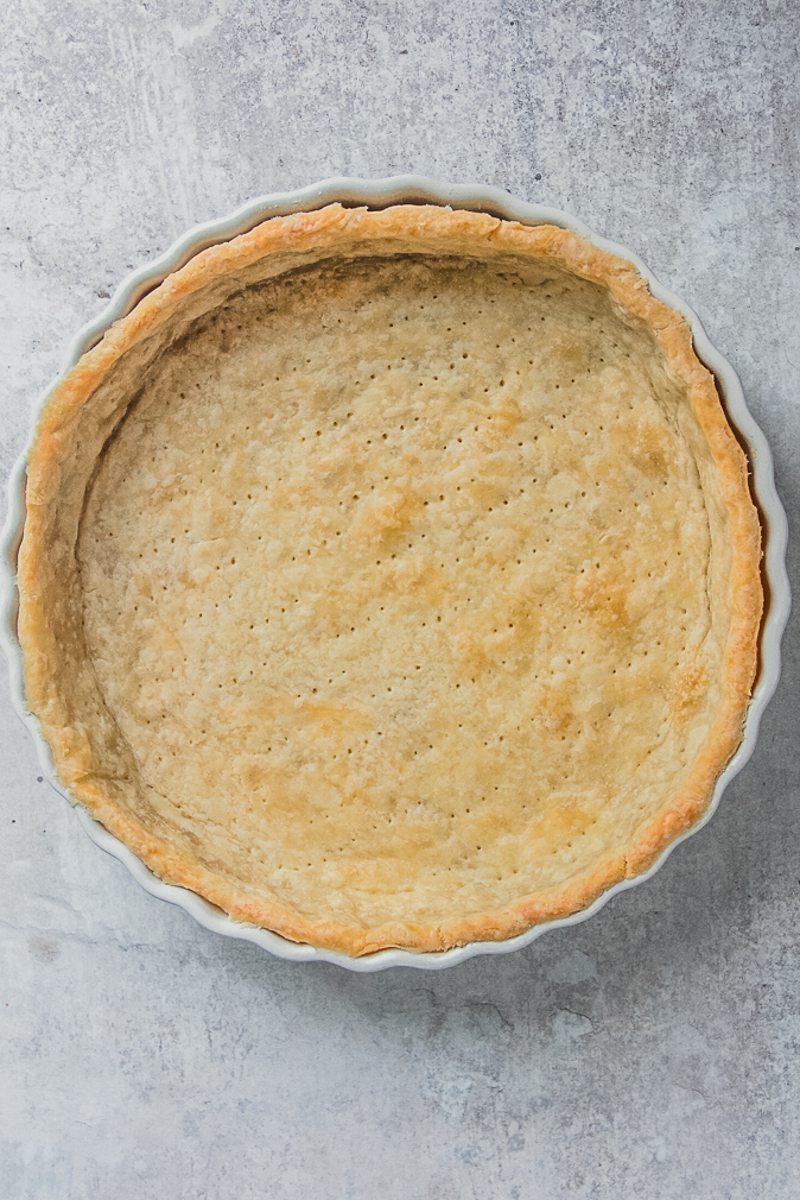 Parbaked pastry sits in a white ceramic baking dish on a gray surface.