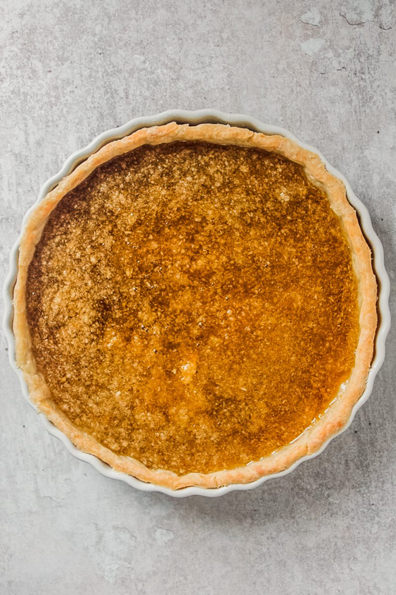 Unbaked treacle tart sits on a gray surface.