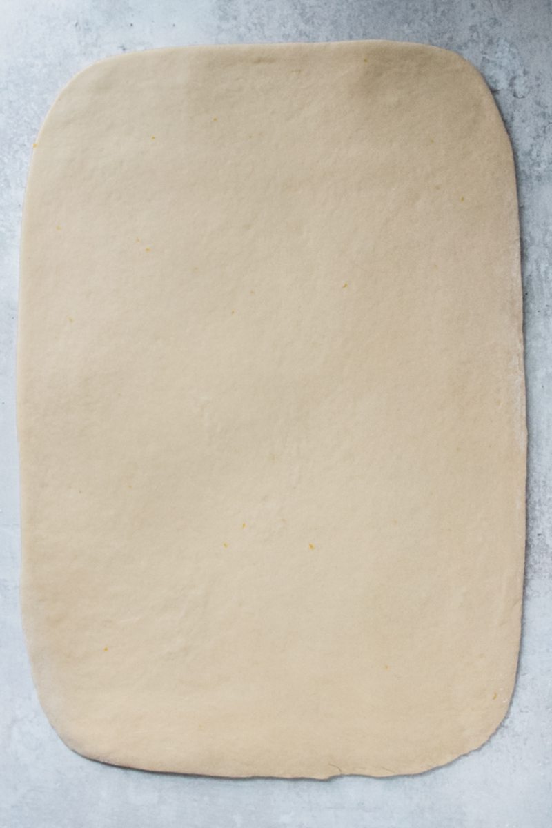 A rectangle of dough sits on a gray surface.