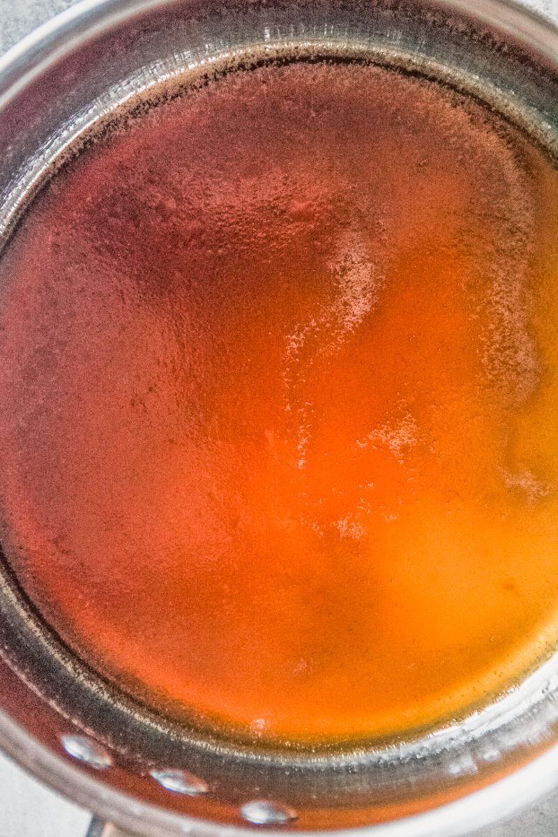 A brown sugar lemon syrup sits in a stainless steel saucepan.