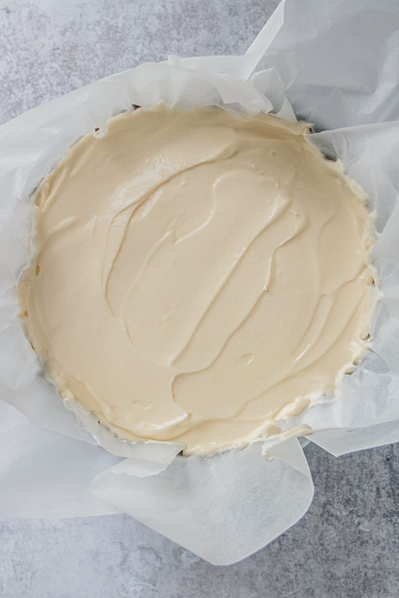 Basque cheesecake batter sits in a lined baking tin on a gray surface.