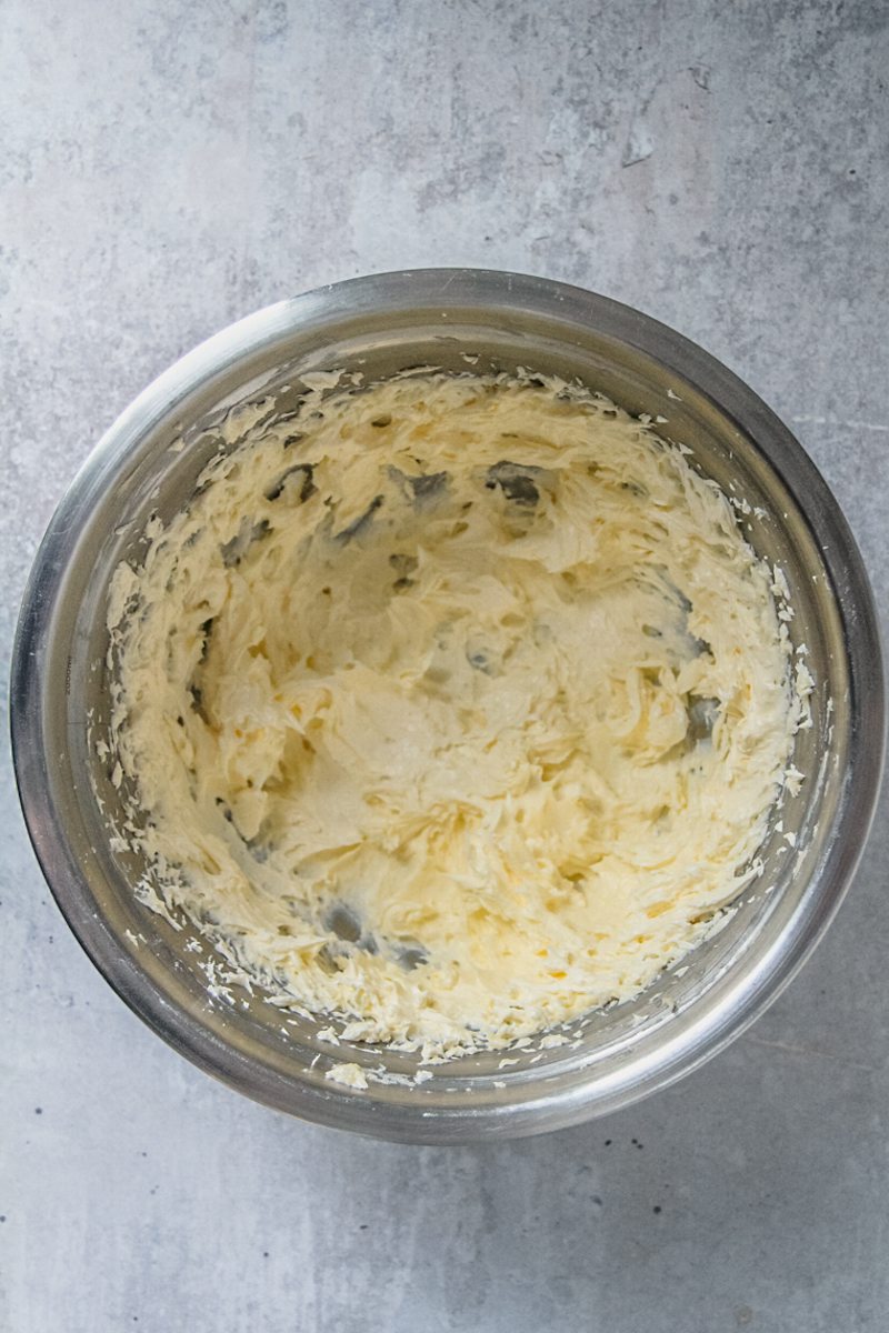 Whipped sugar and butter sit in a stainless steel bowl on a gray surface.