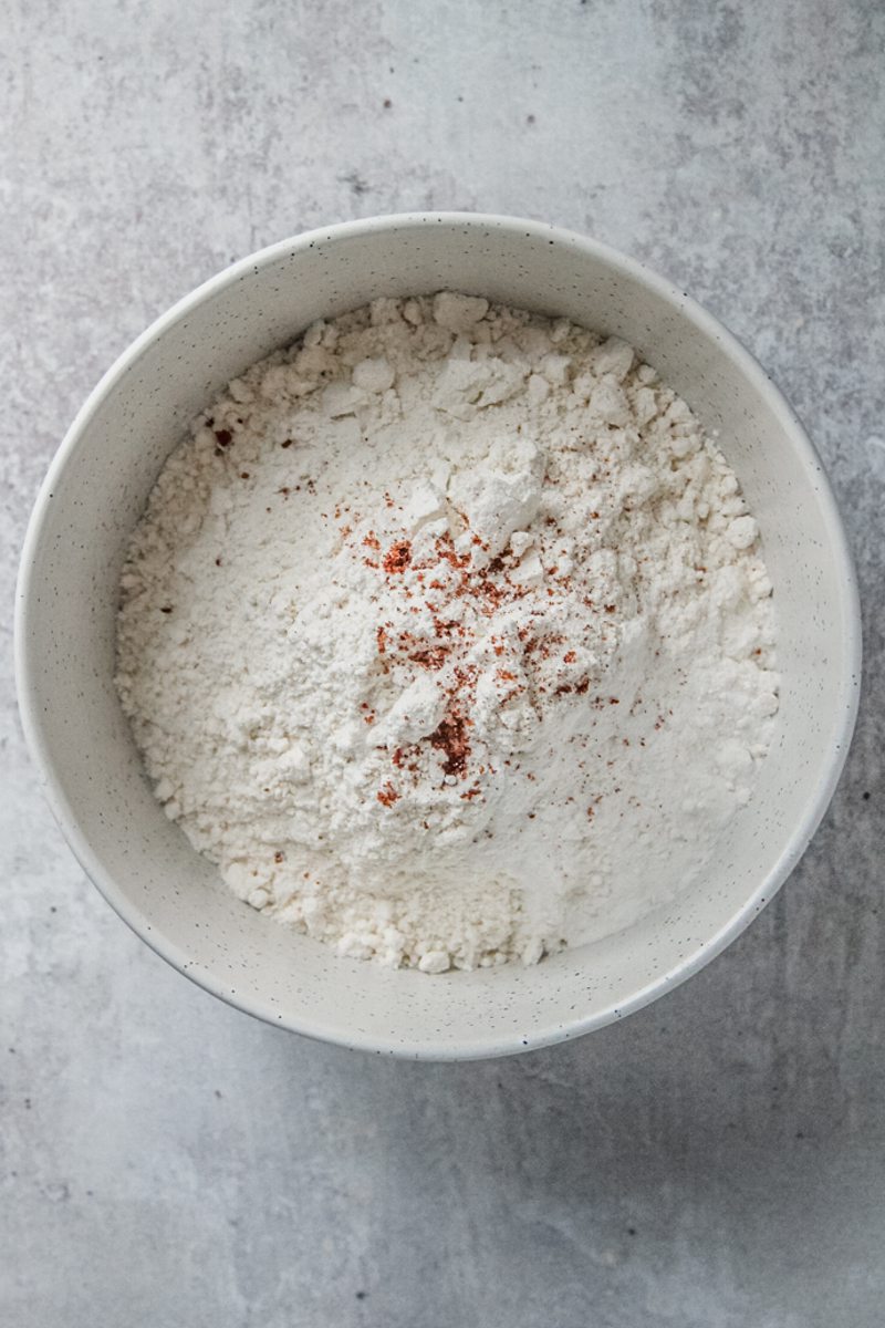 Dry ingredients sit in a white ceramic bowl on a gray surface.