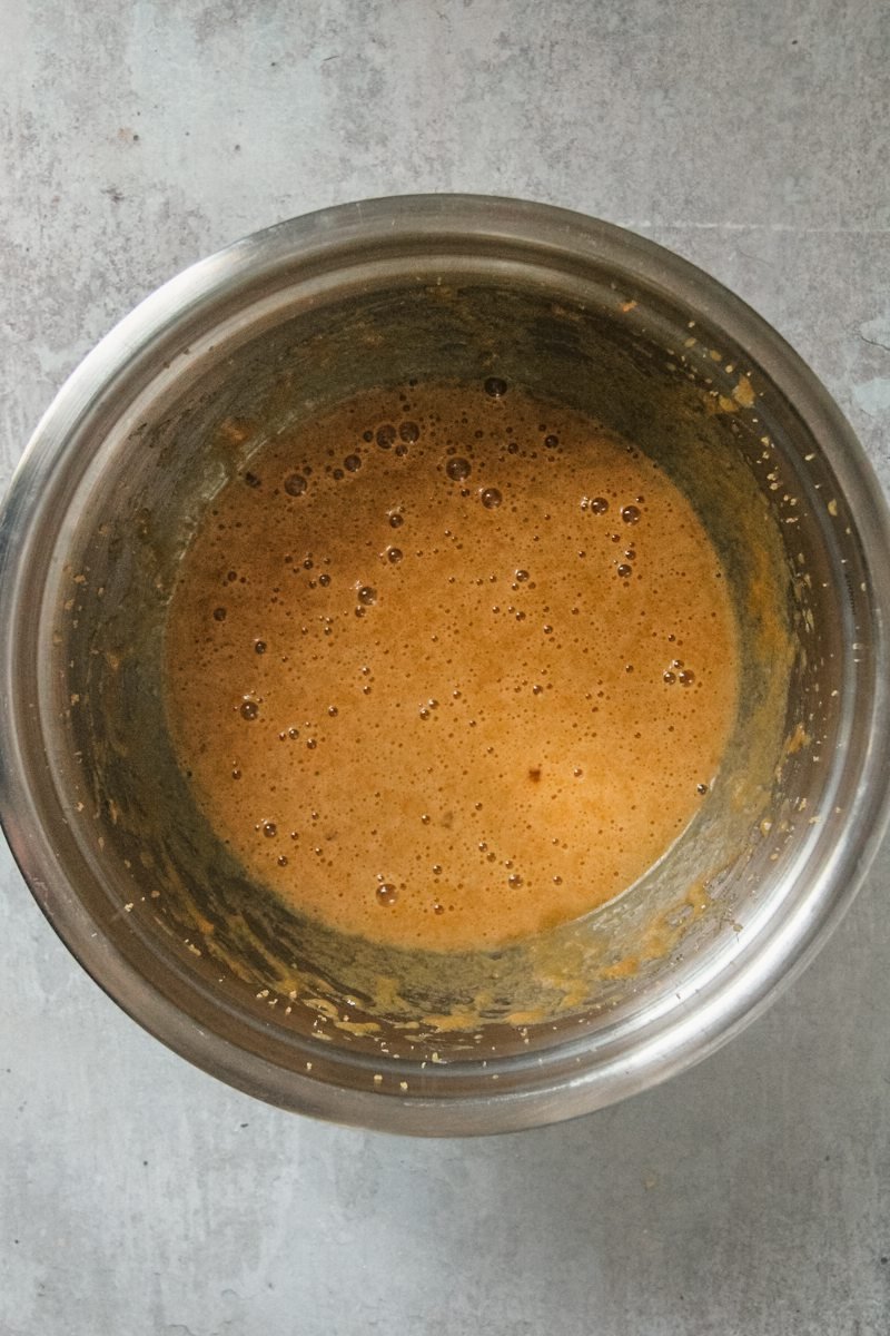 Whipped butter tart filling sits in a stainless steel bowl on a gray surface.