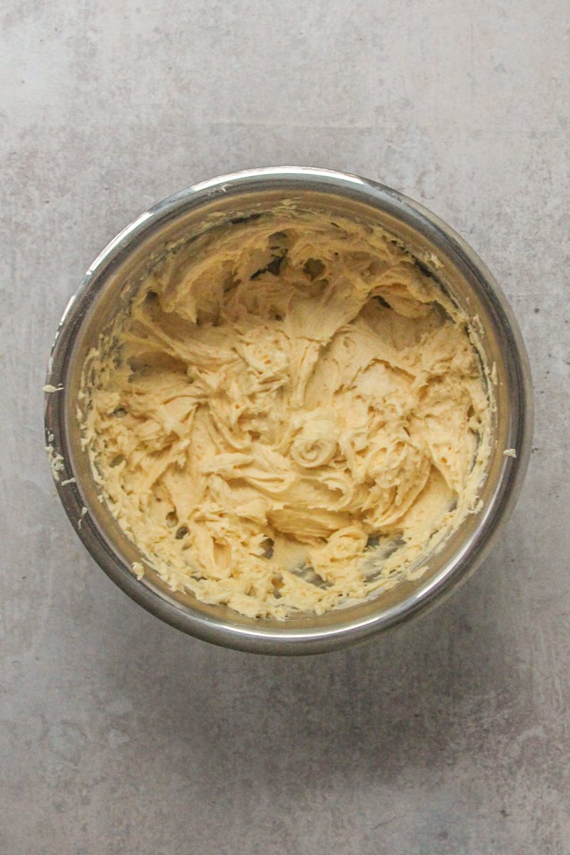 Cake batter sits in a stainless steel bowl on a gray surface.