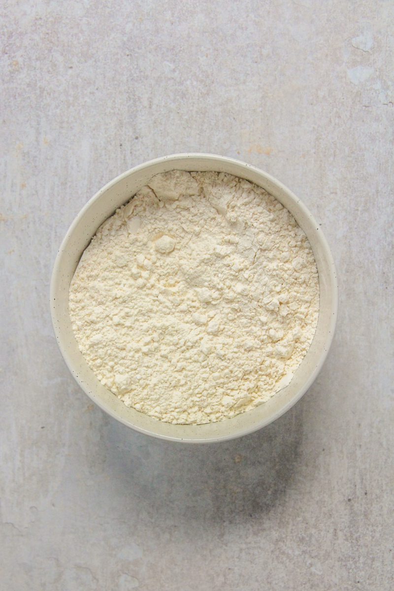 Dry ingredients sit stirred together in a white ceramic bowl on a gray surface.