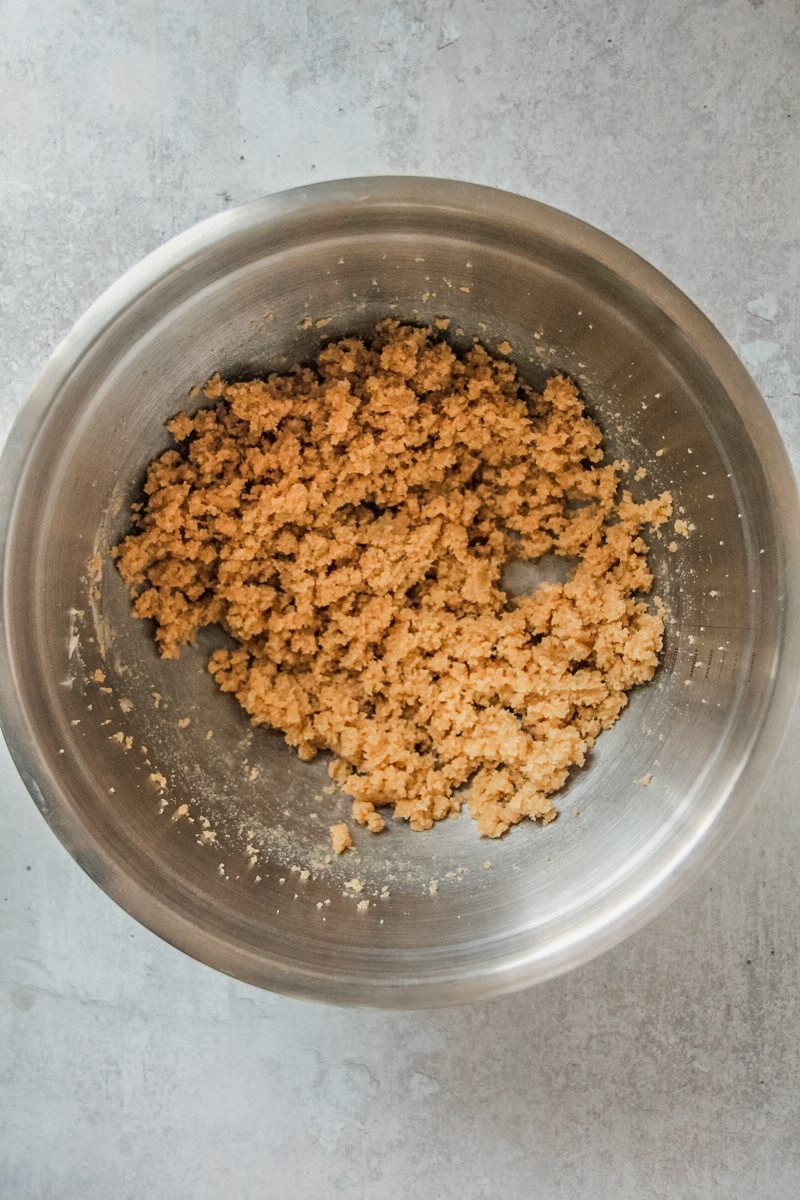 Whipped butter and sugar sit in a stainless steel bowl on a gray surface.