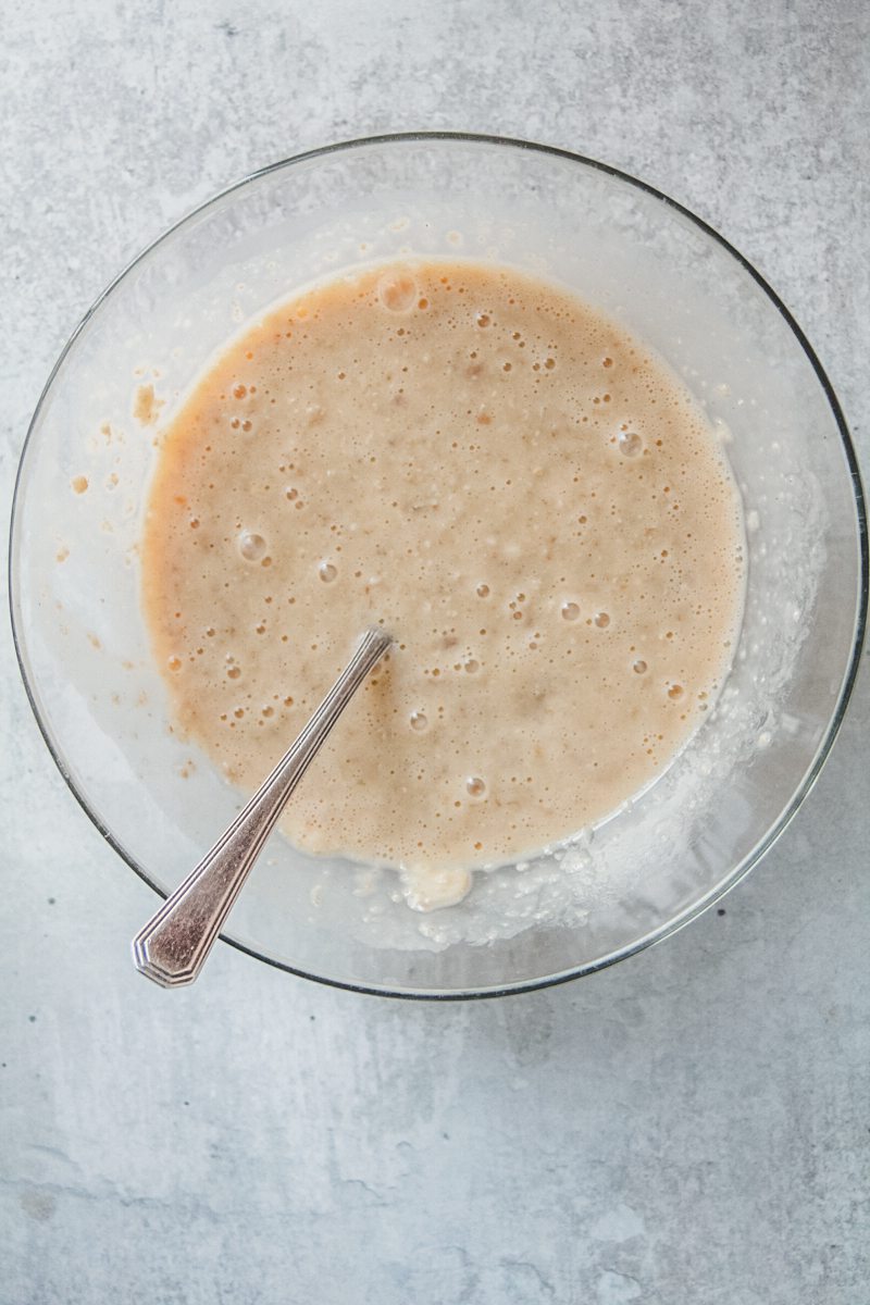 A porridge mixture sits in a glass bowl on a gray surface.