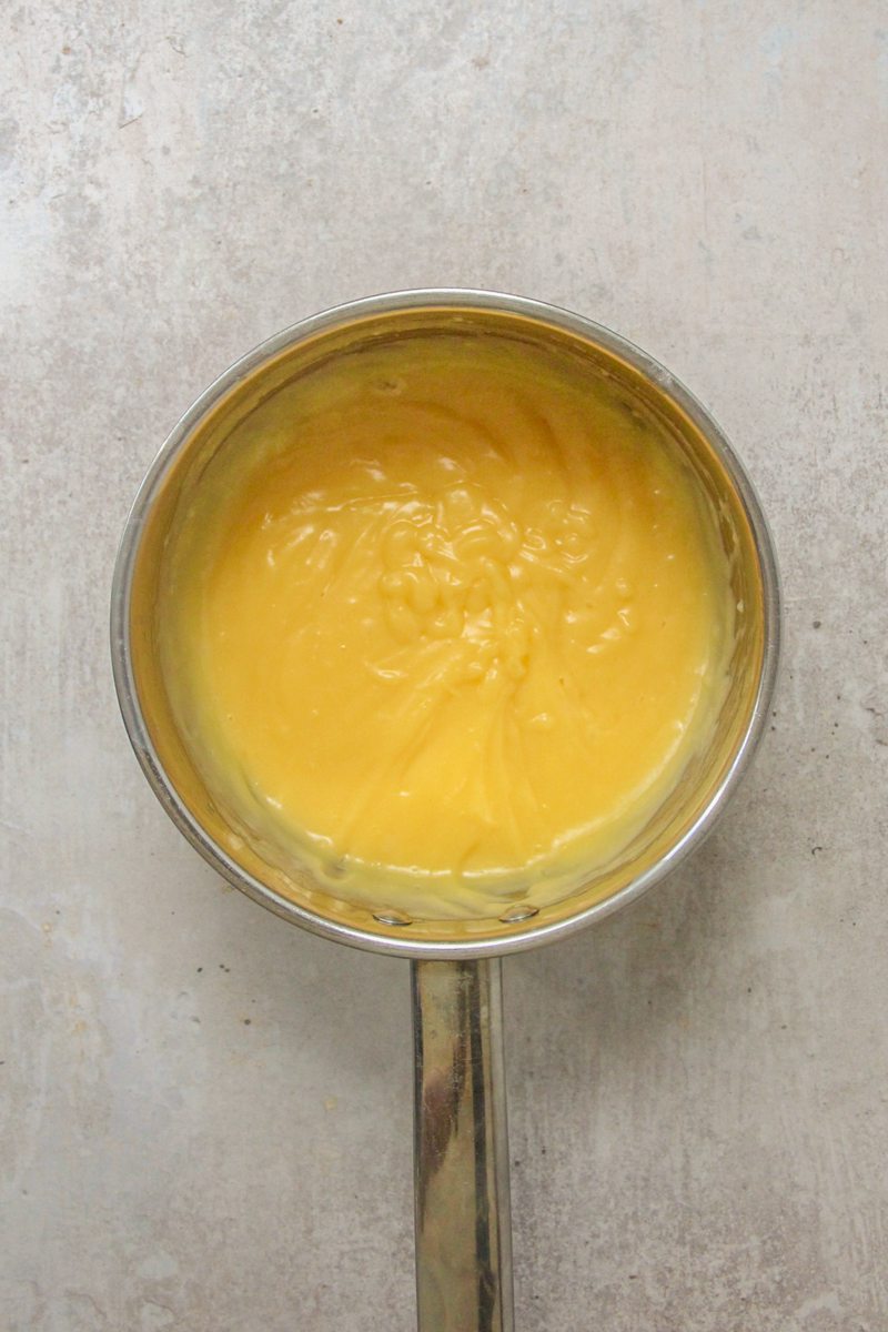 Custard sits in a stainless steel saucepan on a gray surface.