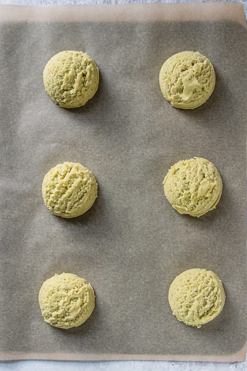 Pistachio sugar cookies sit on a lined baking tray.